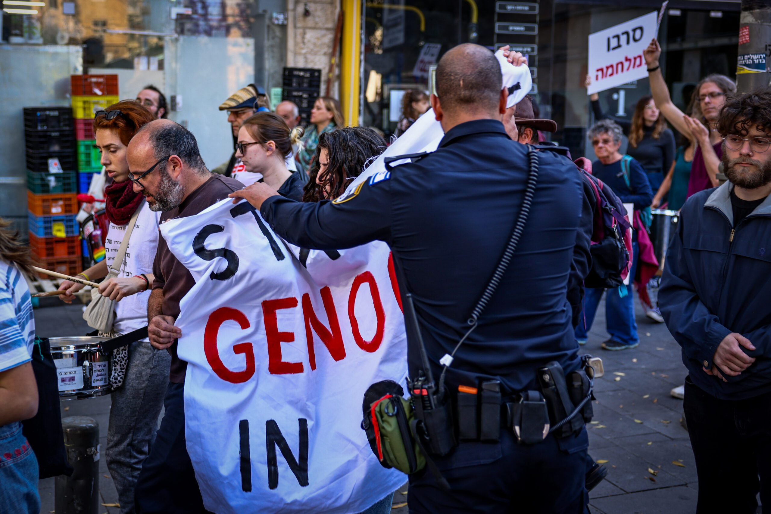 Ein&nbsp;israelischer Polizist konfisziert ein gegen Genozid gerichtetes Banner auf einem linken Protestmarsch gegen den Krieg in Gaza; Jerusalem, 22. November 2024. Foto: Flash90
