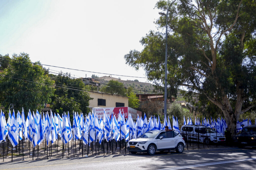 Israeli settlers and security forces stand outside a shop owned by Palestinian Mouayad Oweis after settlers placed dozens of Israeli flags, blocking access to the roadside business in the West Bank village of al-Lubban al-Sharqiya, October 8, 2026. Photo by Flash90