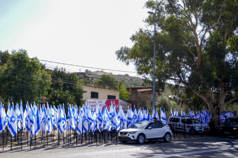 Israeli settlers and security forces stand outside a shop owned by Palestinian Mouayad Oweis after settlers placed dozens of Israeli flags, blocking access to the roadside business in the West Bank village of al-Lubban al-Sharqiya, October 8, 2026. Photo by Flash90